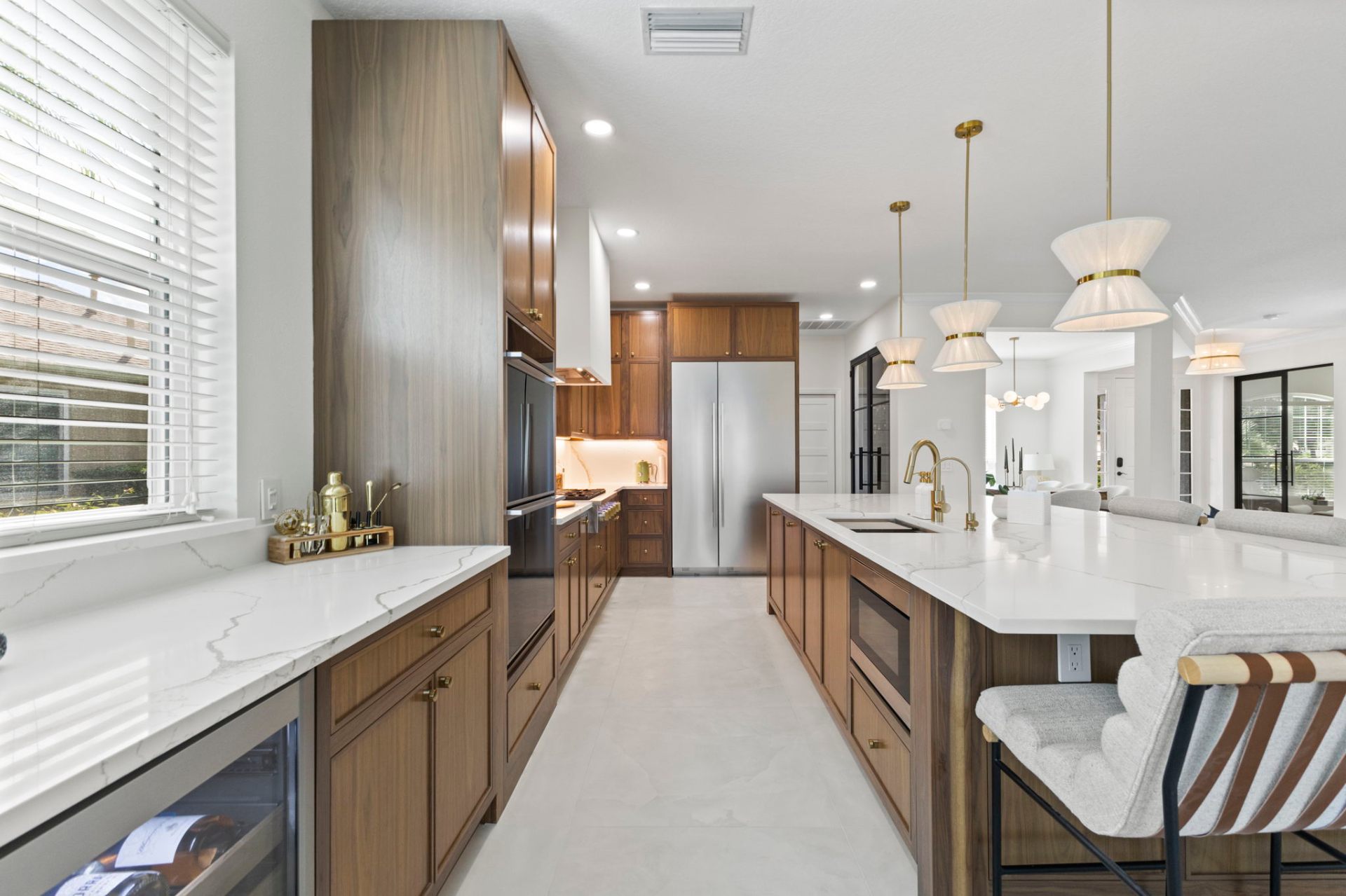 Galley view of walnut cabinetry with integrated appliances and brass hardware