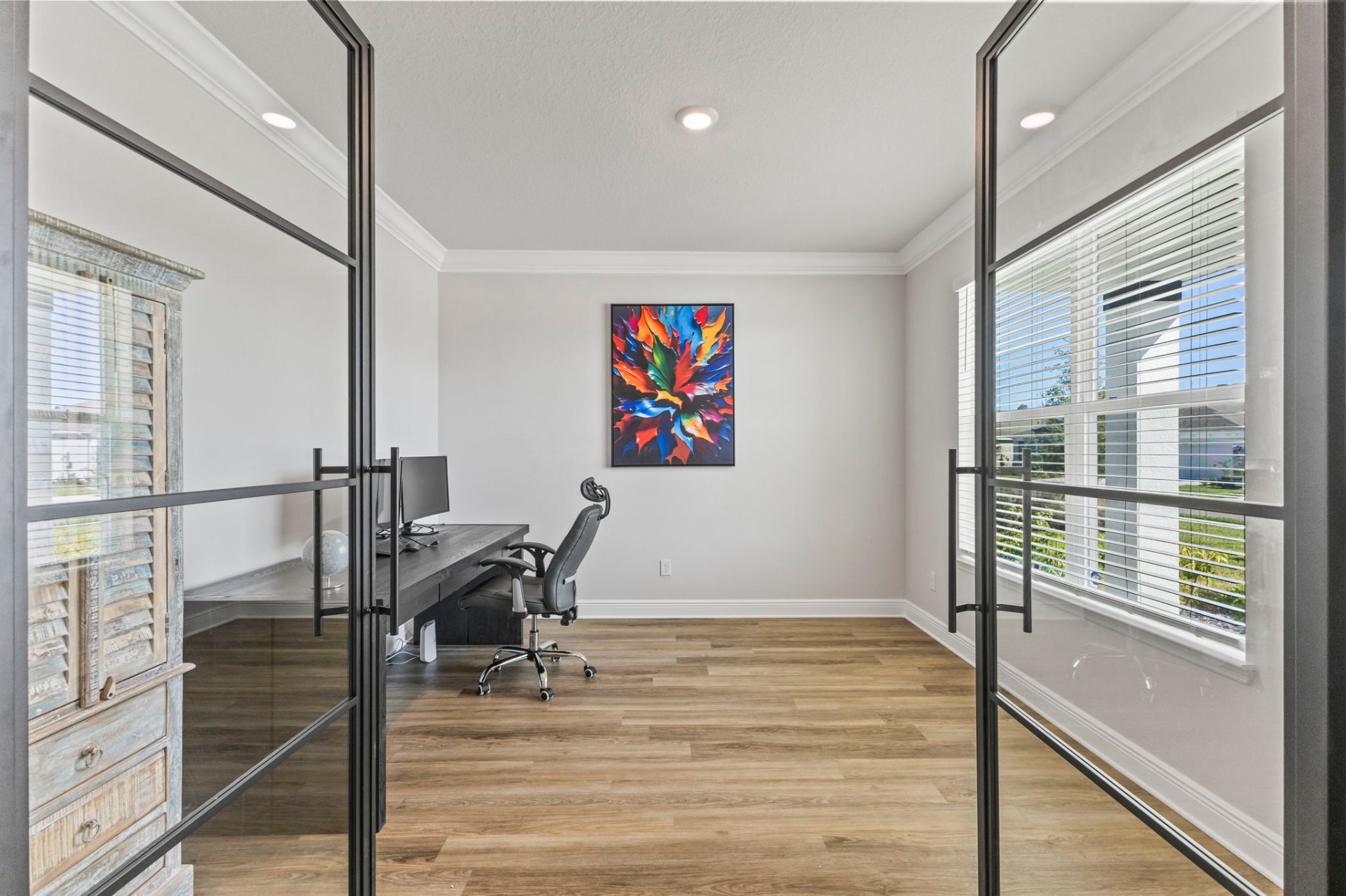 Custom glass-enclosed home office with steel-frame doors and bespoke desk