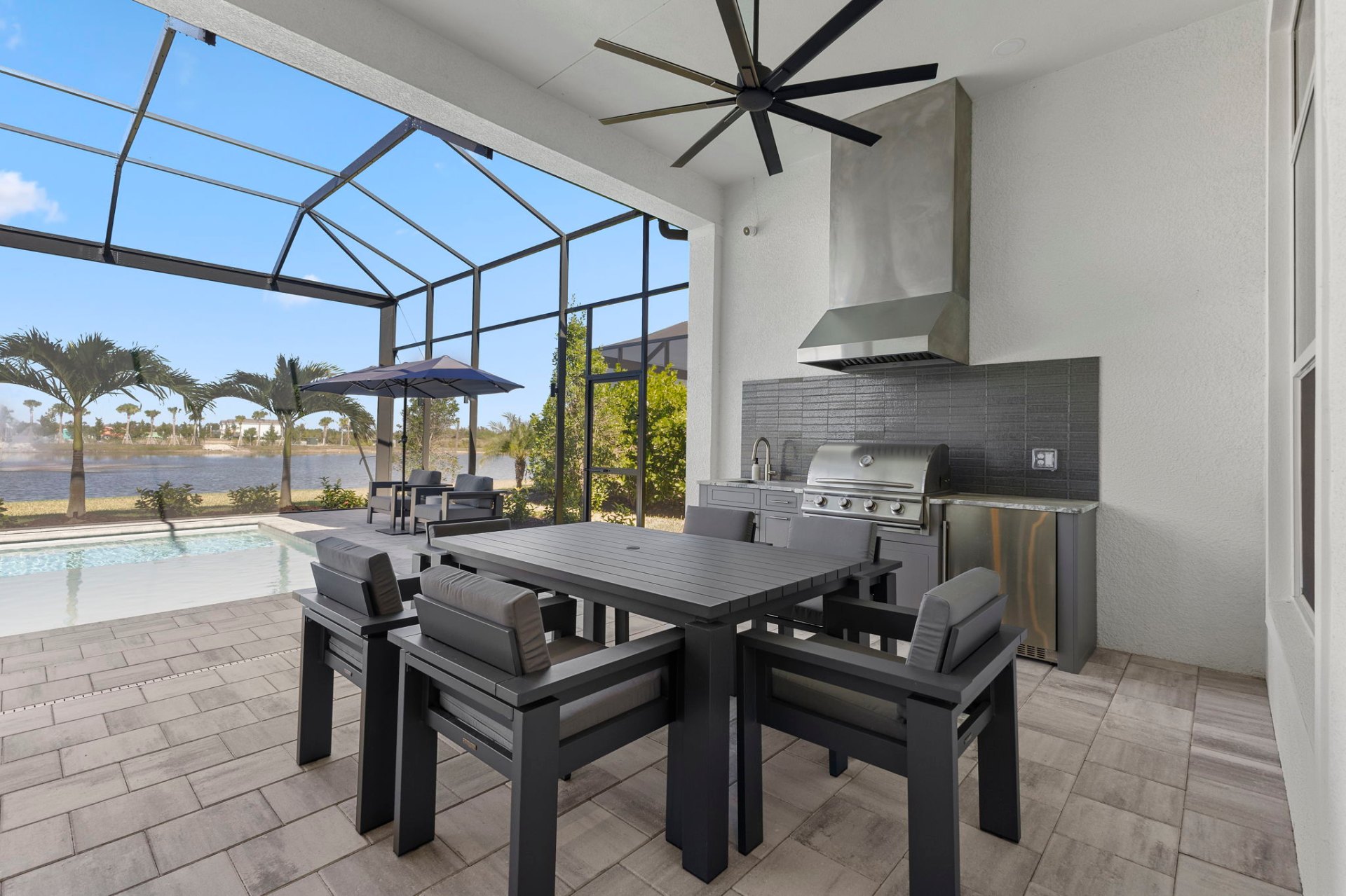 Outdoor kitchen with stainless grill and lakefront pool deck
