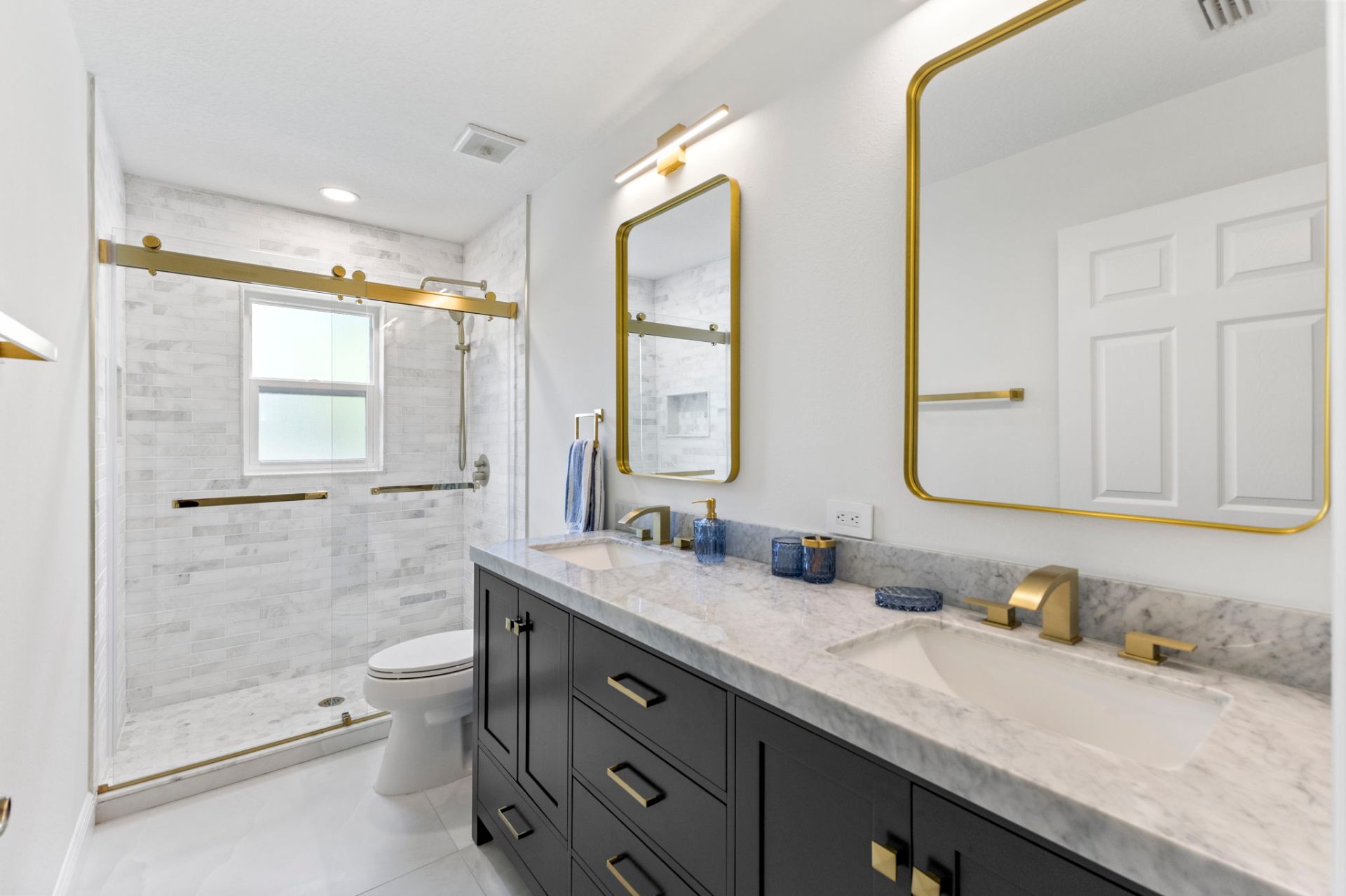 Renovated guest bathroom with marble vanity, brass fixtures and walk-in marble shower