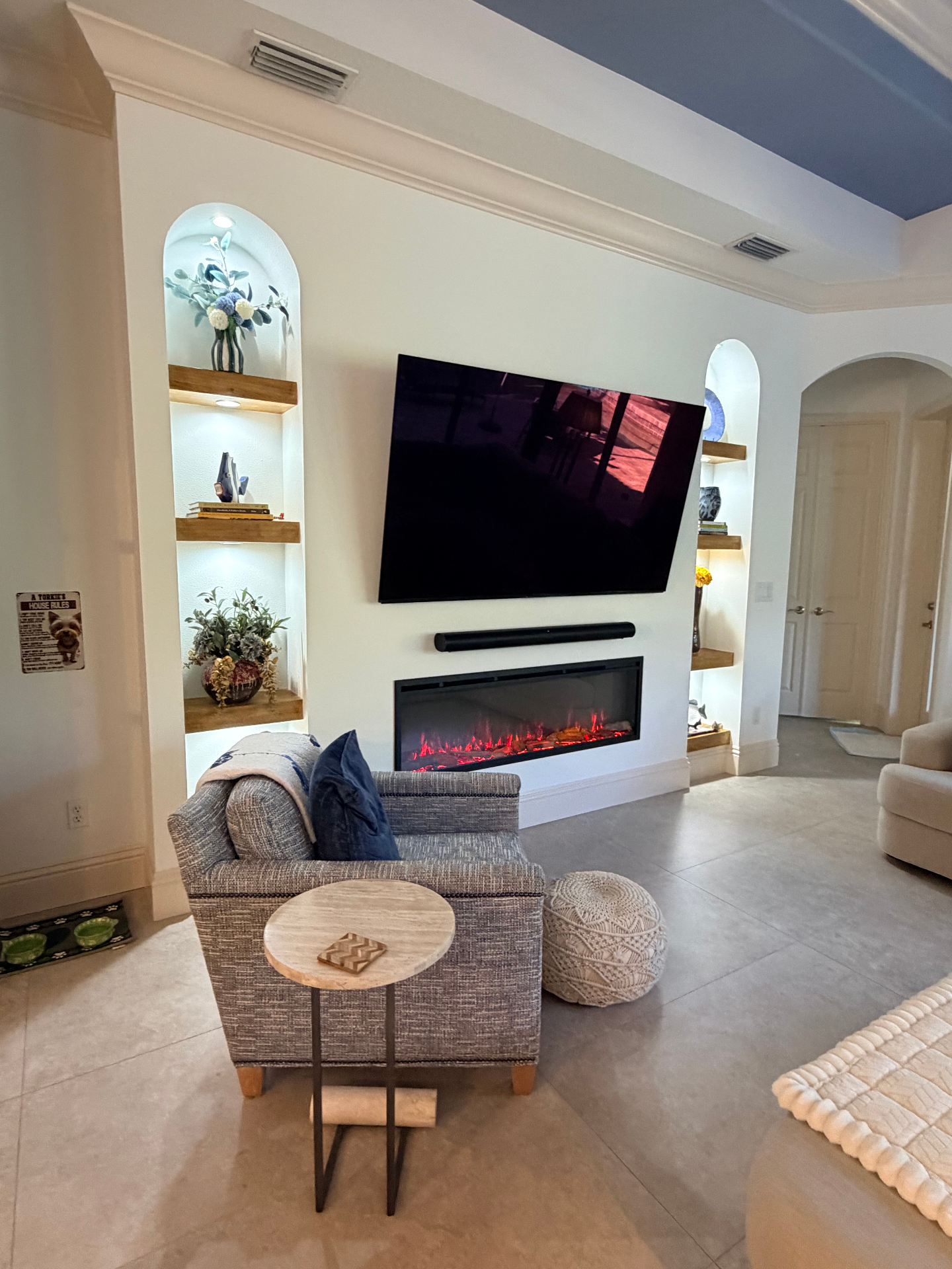 Living room feature wall with arched display niches, floating wood shelves and contemporary linear fireplace