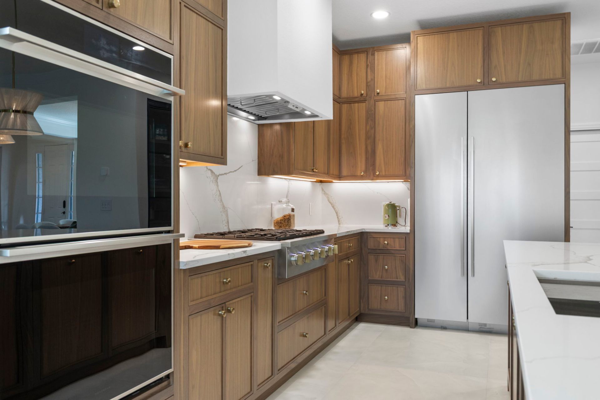 Walnut perimeter cabinetry with integrated panel refrigerator and double ovens
