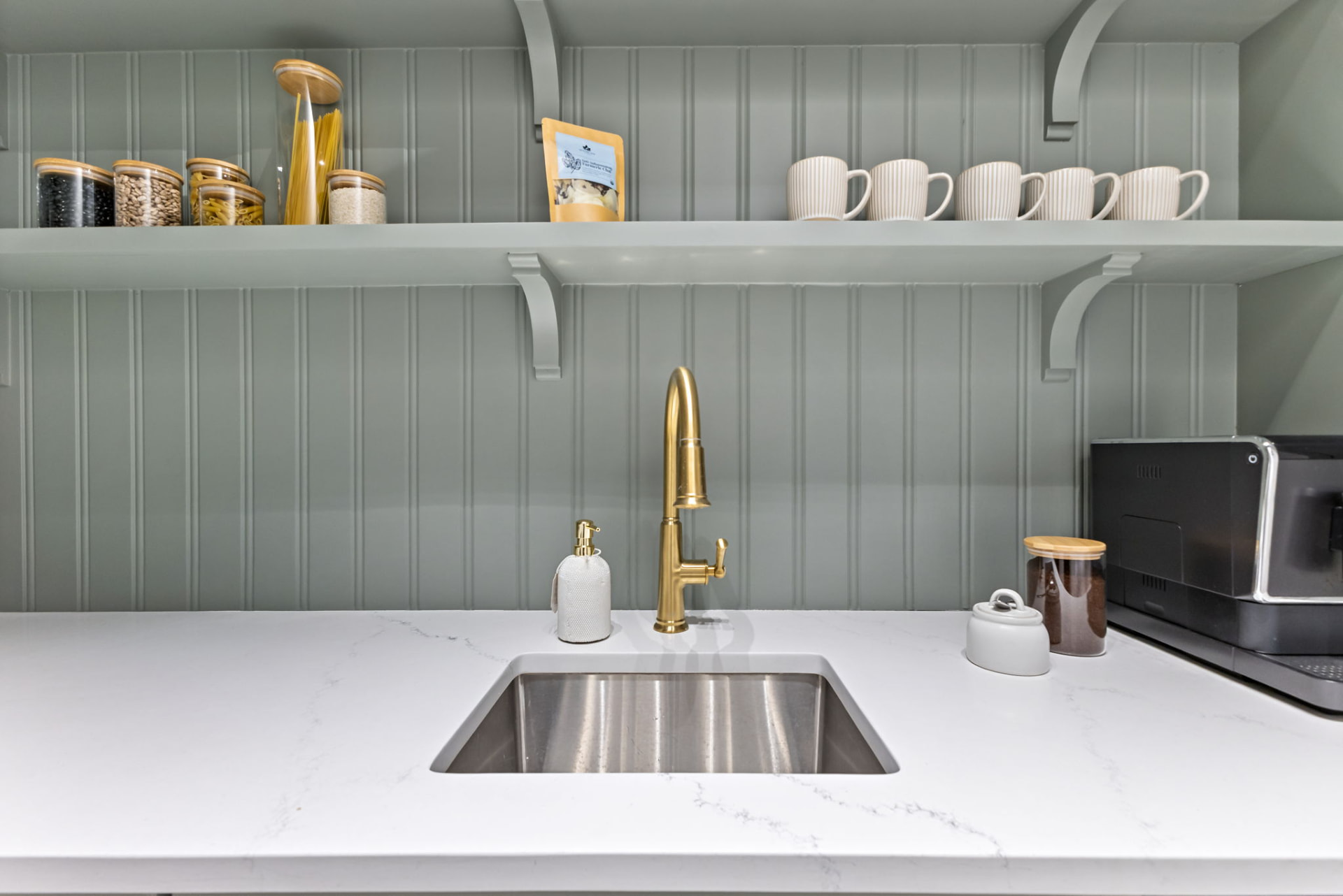 Undermount prep sink with brass faucet beneath handcrafted open shelving