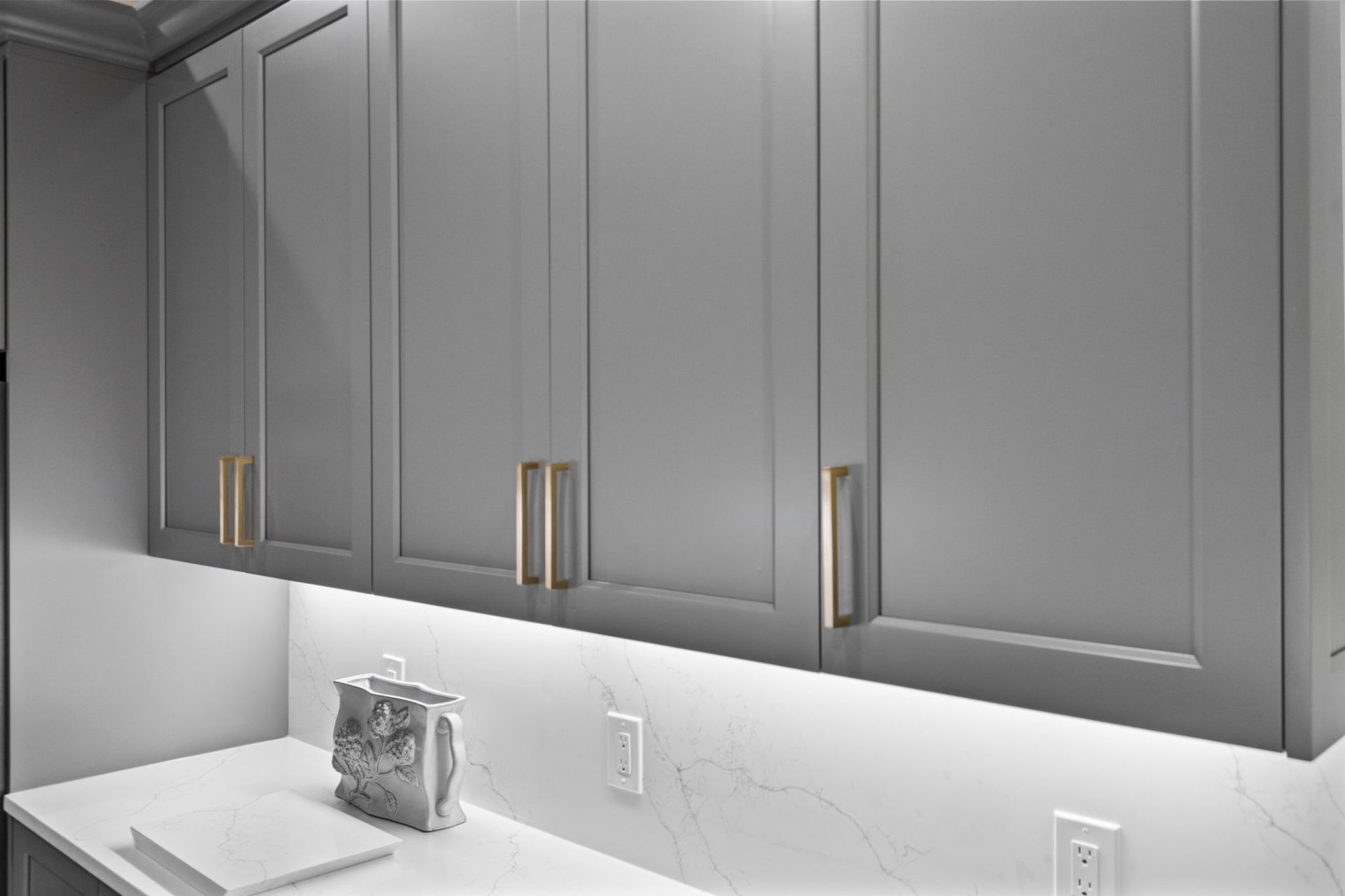 Upper cabinetry detail showing custom Gauntlet Gray finish and champagne bronze hardware
