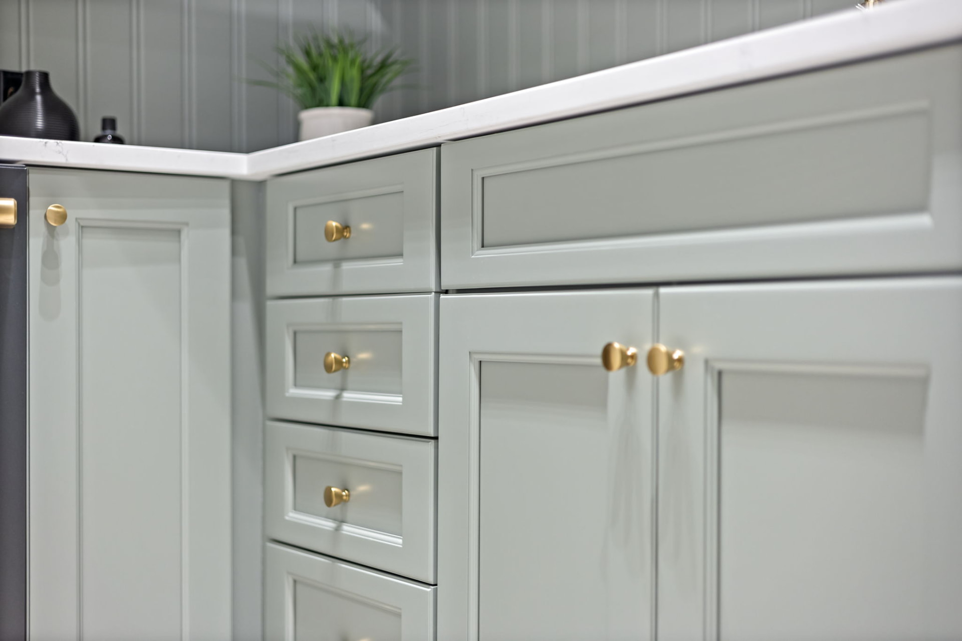 Close-up of custom inset pantry cabinetry with brass knobs and quartz countertop