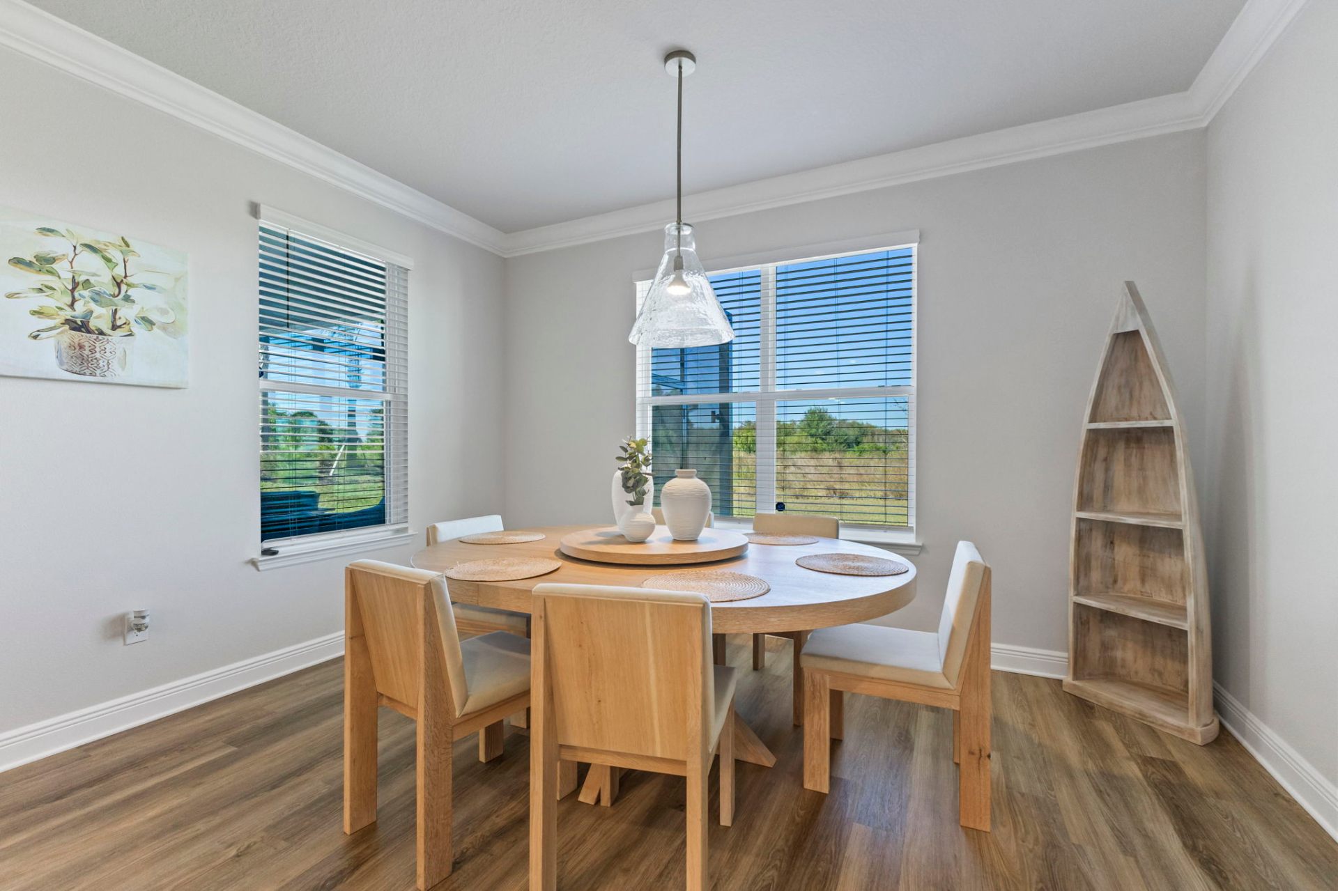 Breakfast nook with round oak table, coastal artwork and natural light