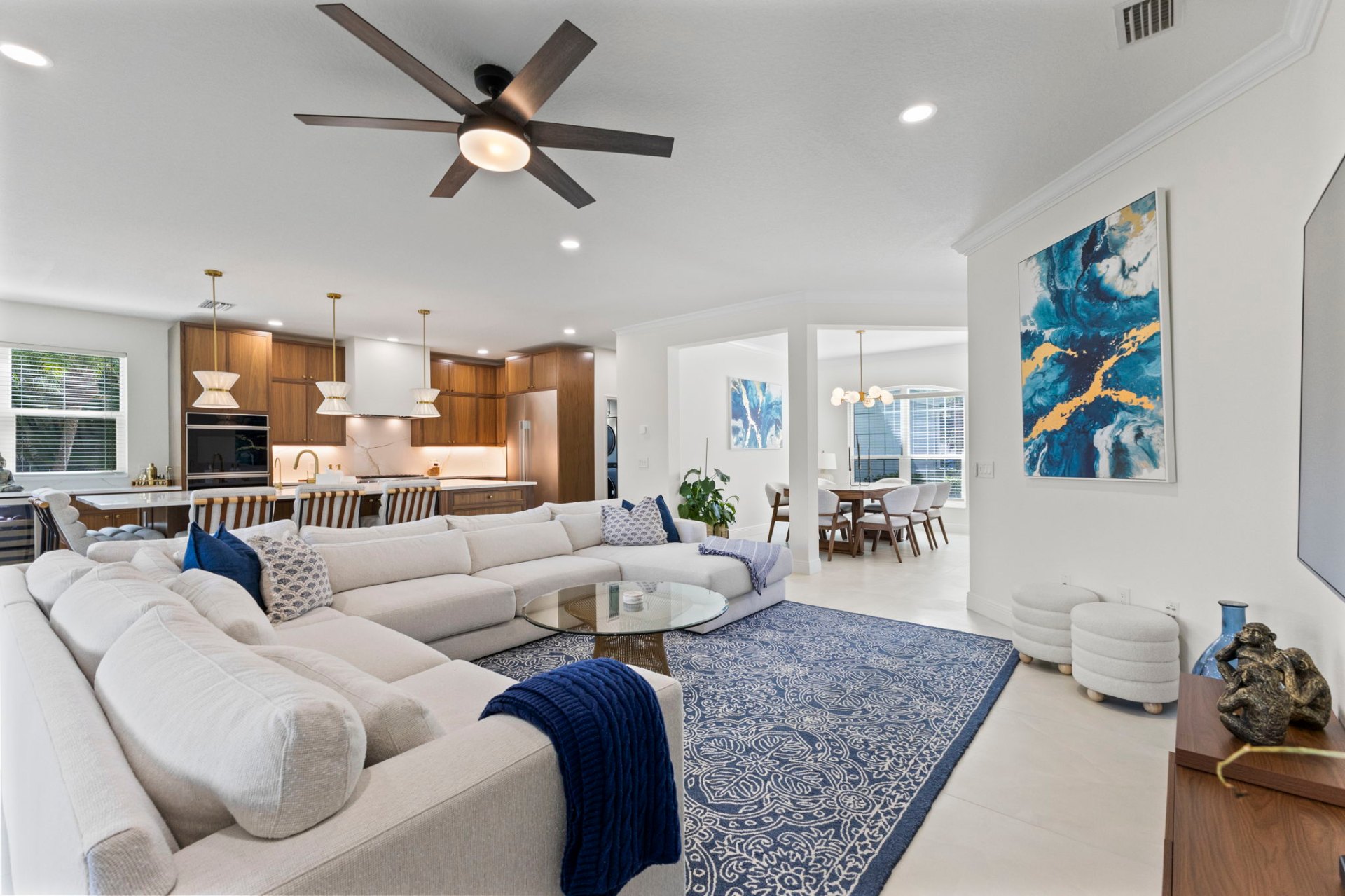Open-concept living room with sectional sofa, blue accents and view through to the walnut kitchen and dining
