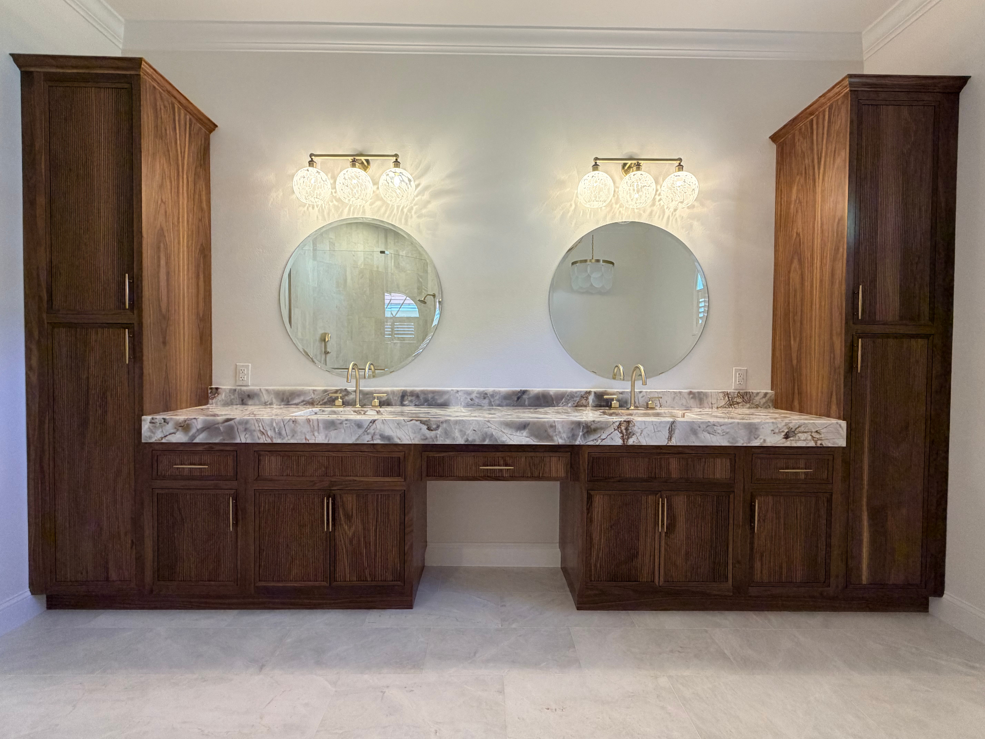 Custom solid walnut dual vanity with twin linen towers, round mirrors and bookmatched quartzite countertop in Laurel Oaks Lakewood Ranch