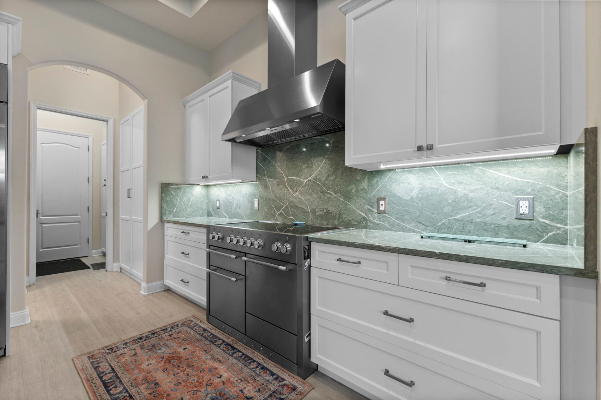 Stainless steel range hood with green natural stone backsplash
