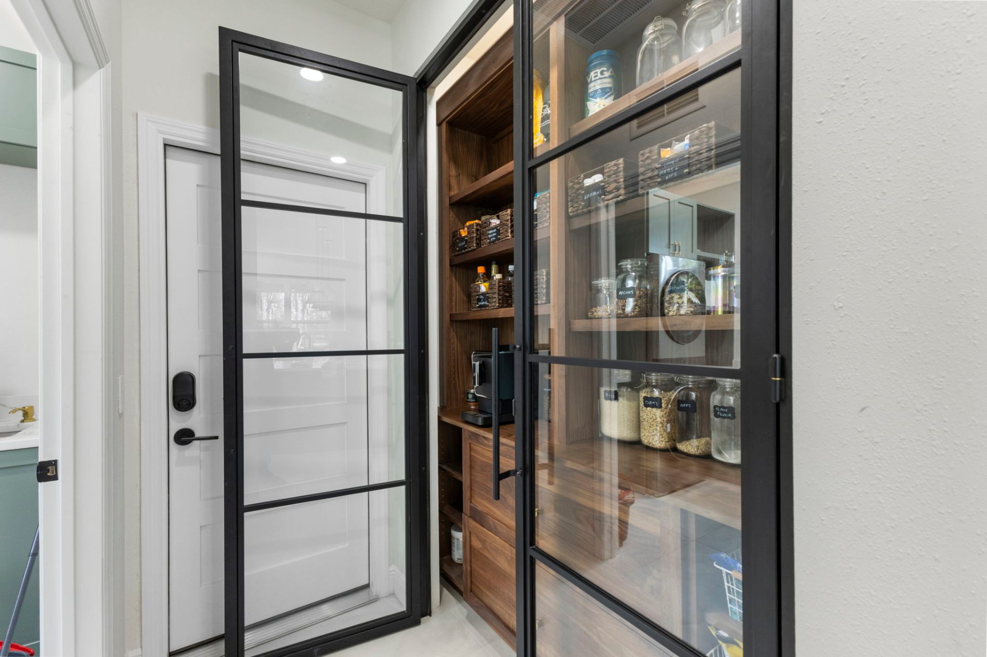 Custom walnut pantry with black aluminum-framed glass doors and integrated coffee station