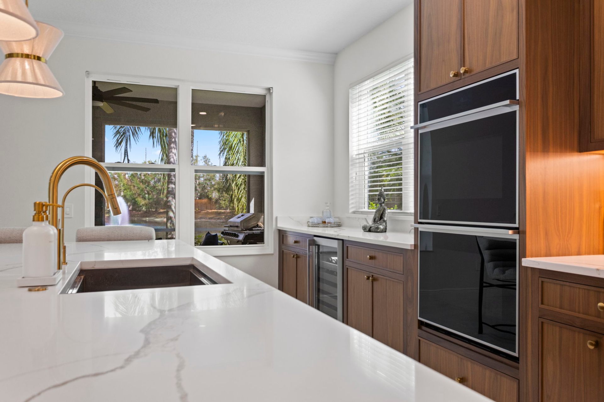 Prep sink, beverage center and double wall ovens framed in walnut cabinetry