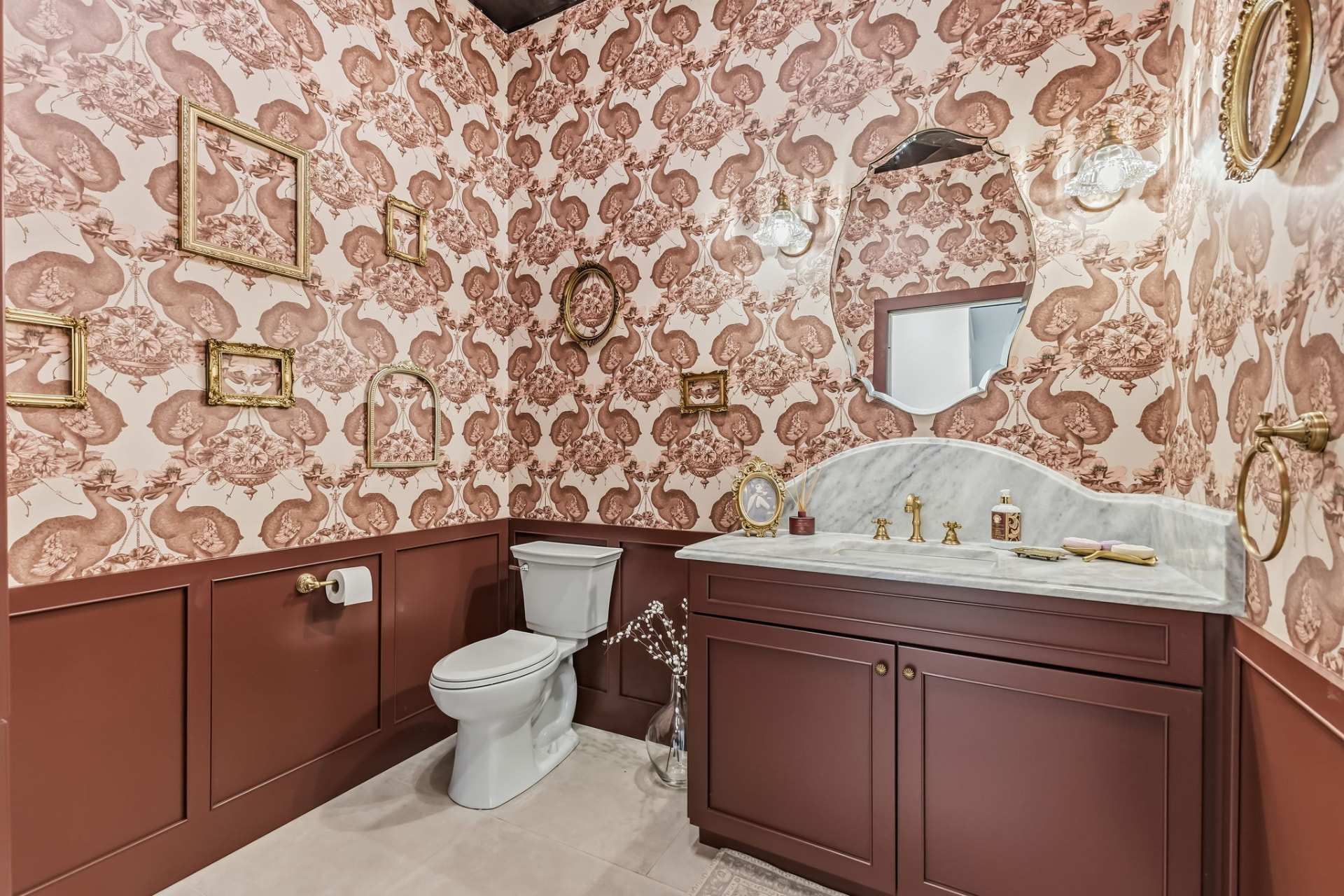 Powder room with patterned wallpaper, deep red custom vanity cabinetry and marble countertop