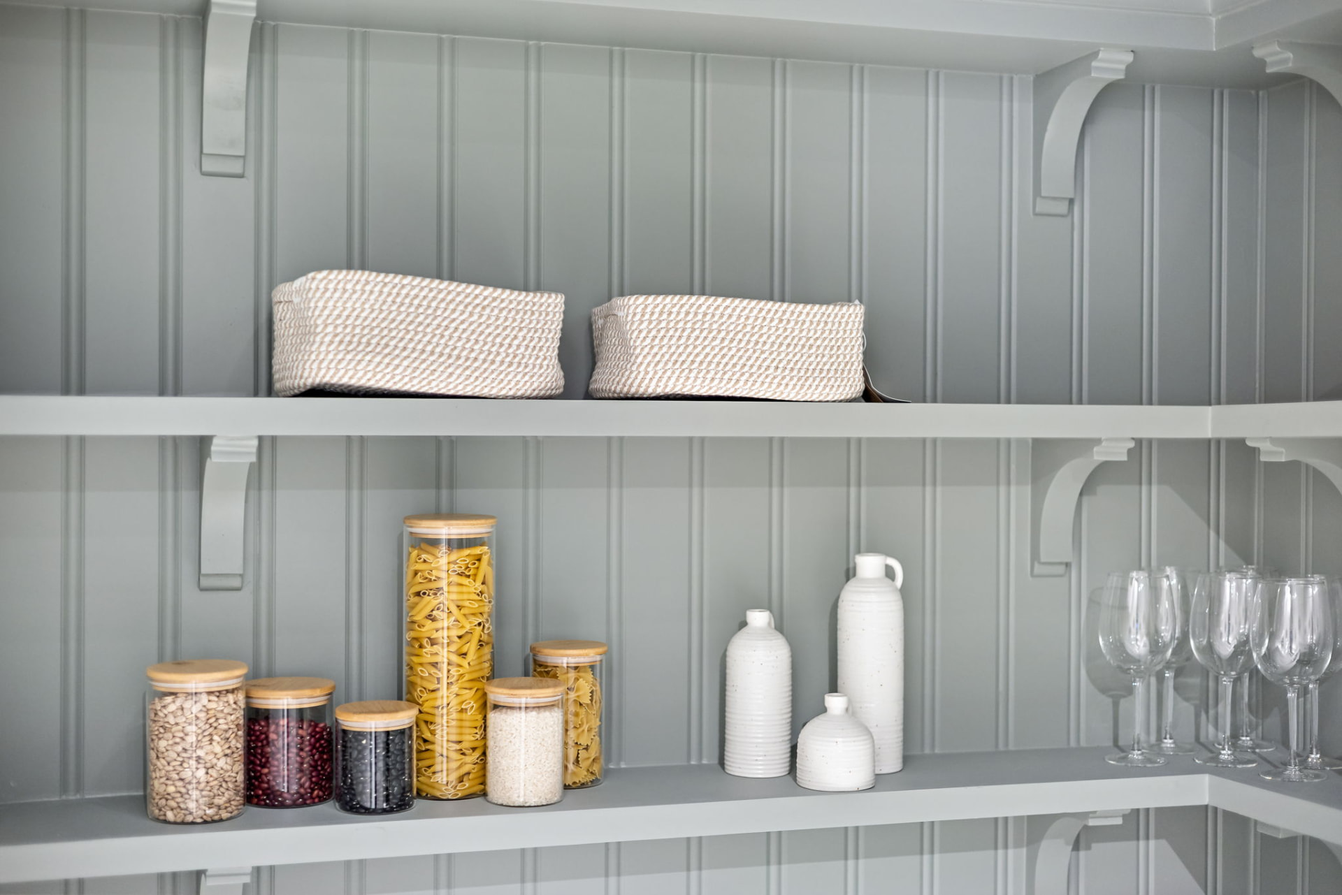 Open pantry shelving with handcrafted corbels holding glassware and dry goods
