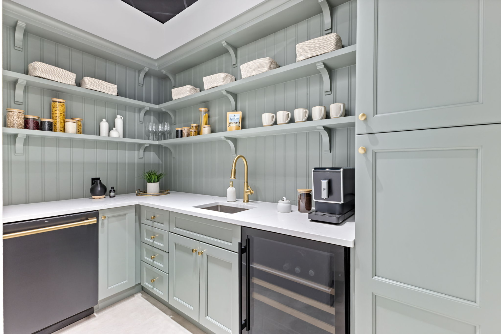 Custom sage green walk-in pantry with open shelving, quartz counters and brass hardware