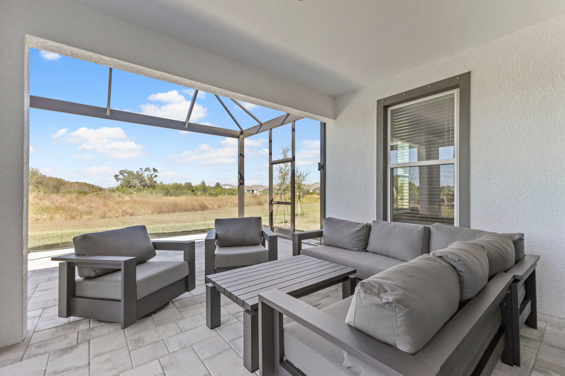 Screened lanai with grey outdoor sectional and preserve views