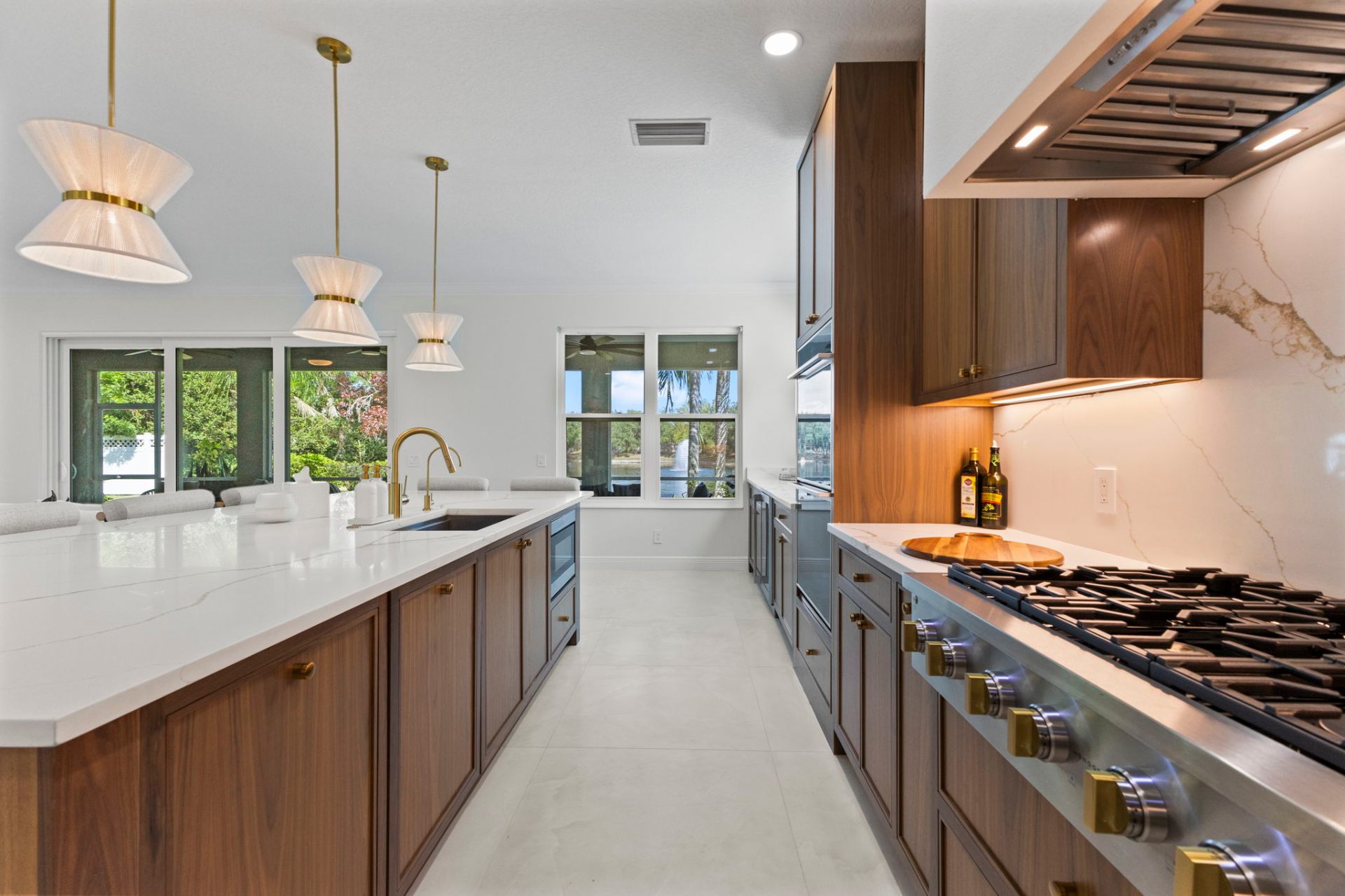 Walnut island and gas range with calacatta quartz backsplash overlooking the lake