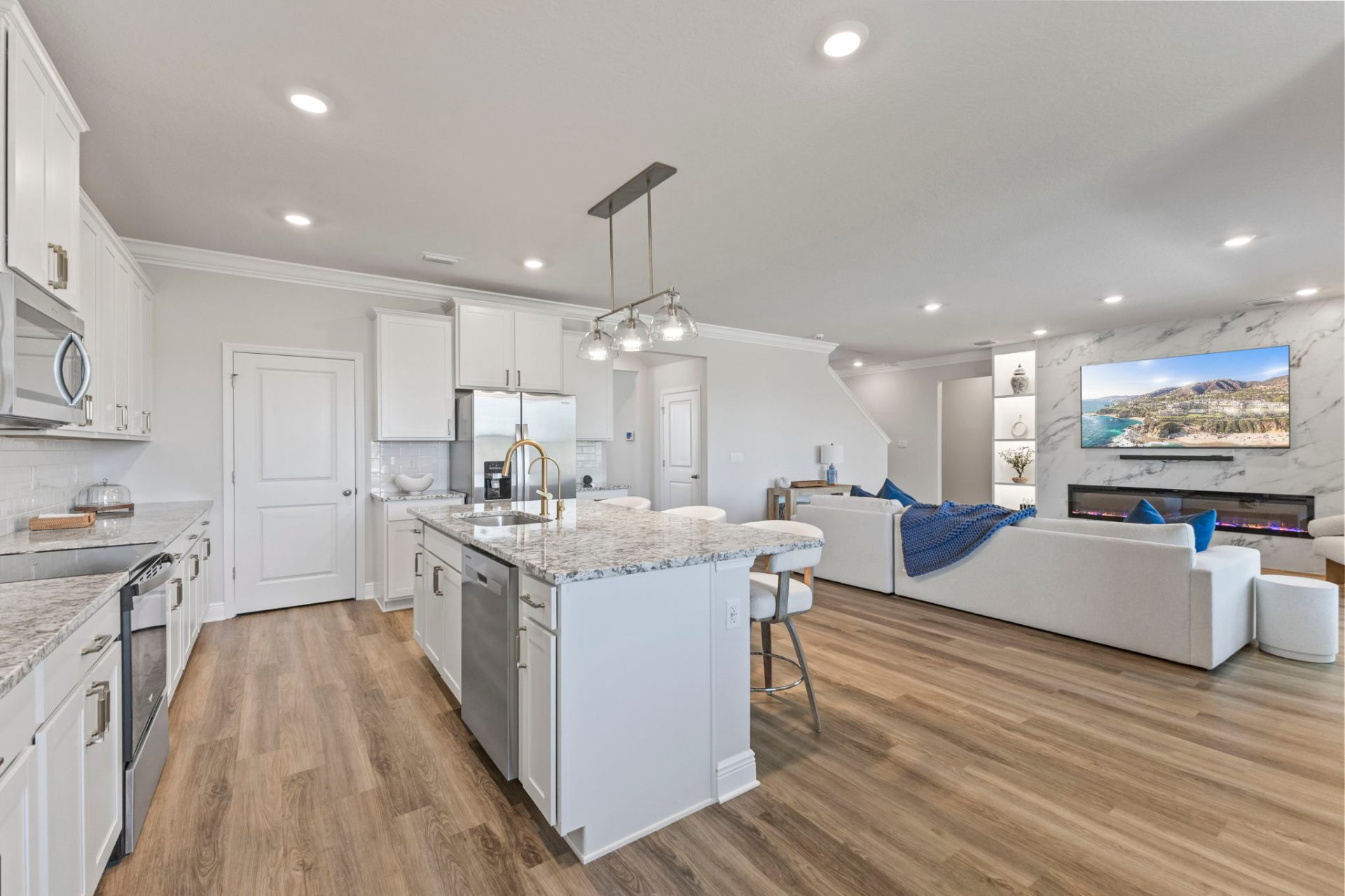 Open kitchen and living room with marble feature wall, linear fireplace and granite island