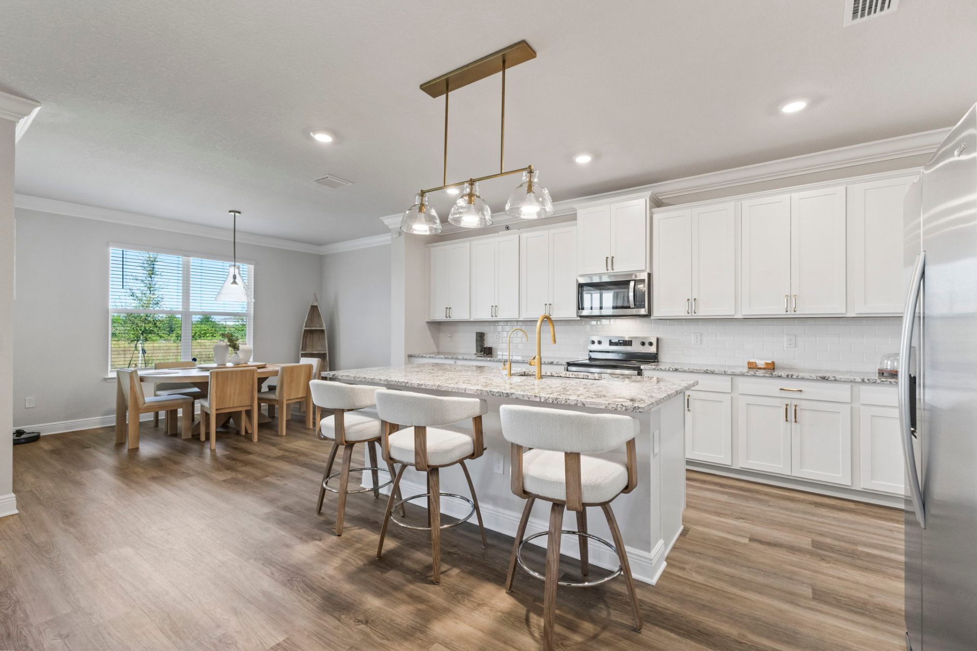 Star Farms kitchen with white shaker cabinetry, brass pendant lighting and granite island