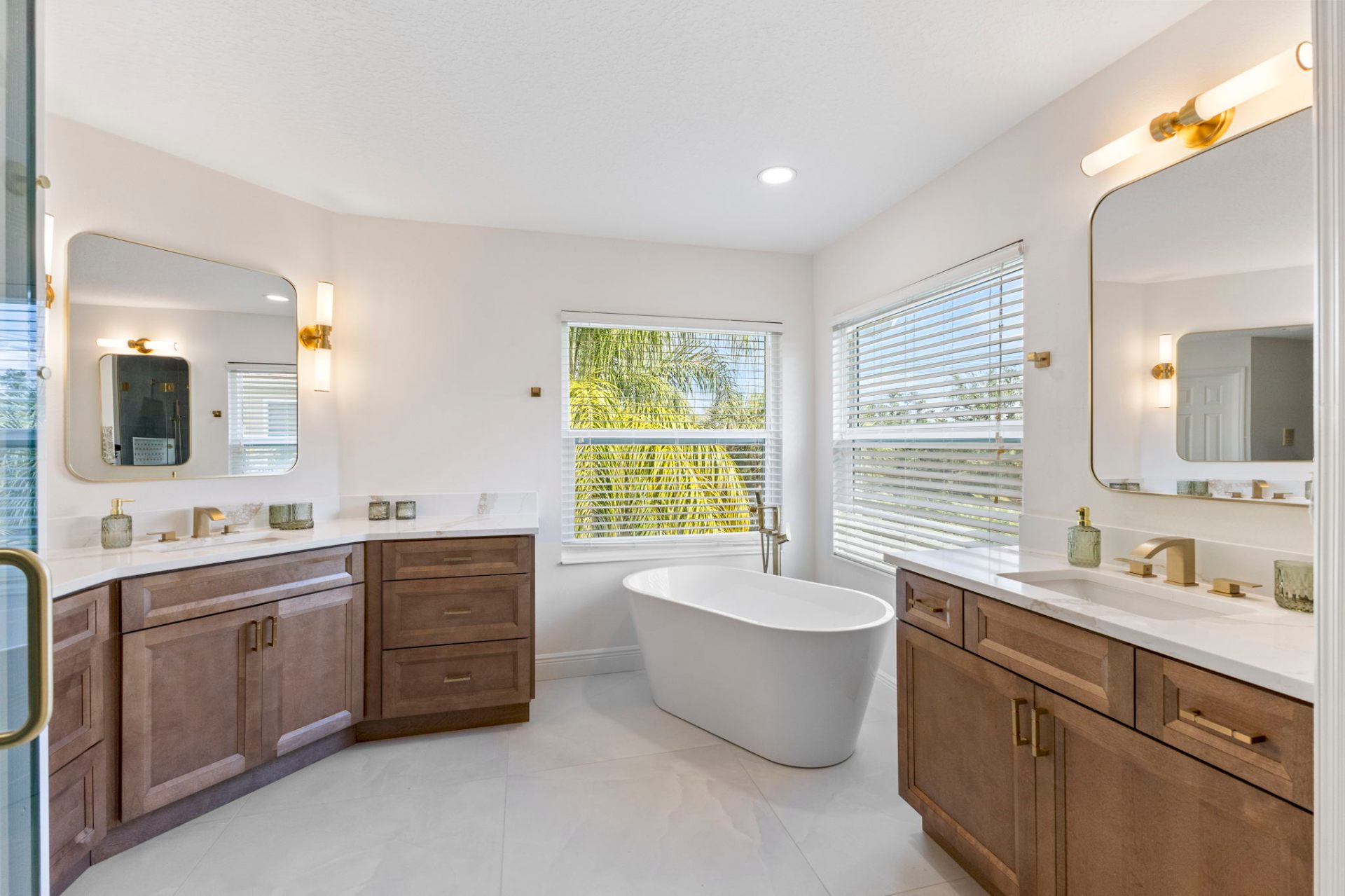 Primary bathroom with twin custom wood vanities, freestanding soaking tub and brass fixtures