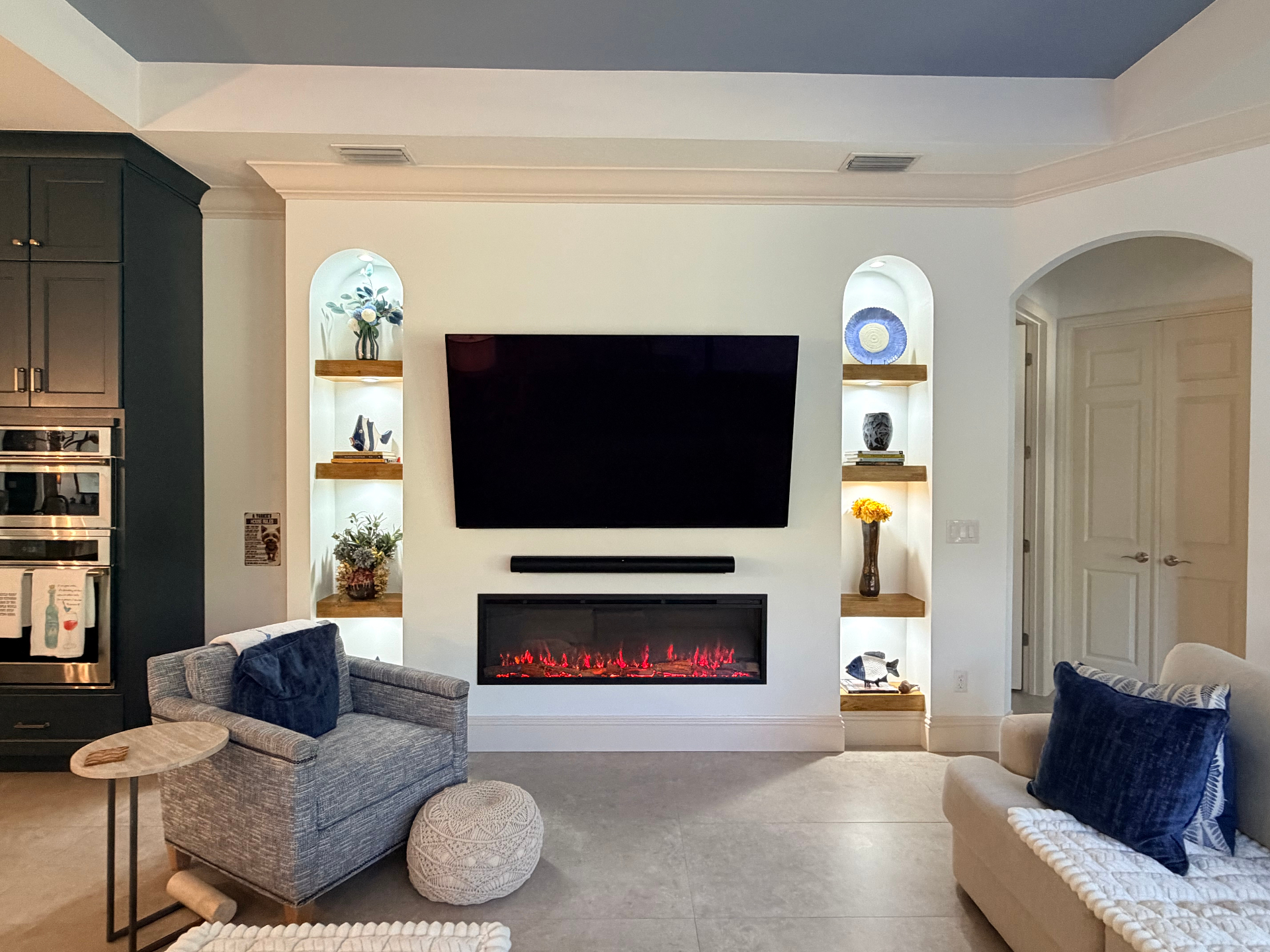 Custom modern Mediterranean media wall with integrated TV, linear fireplace and arched alcoves with solid wood shelving