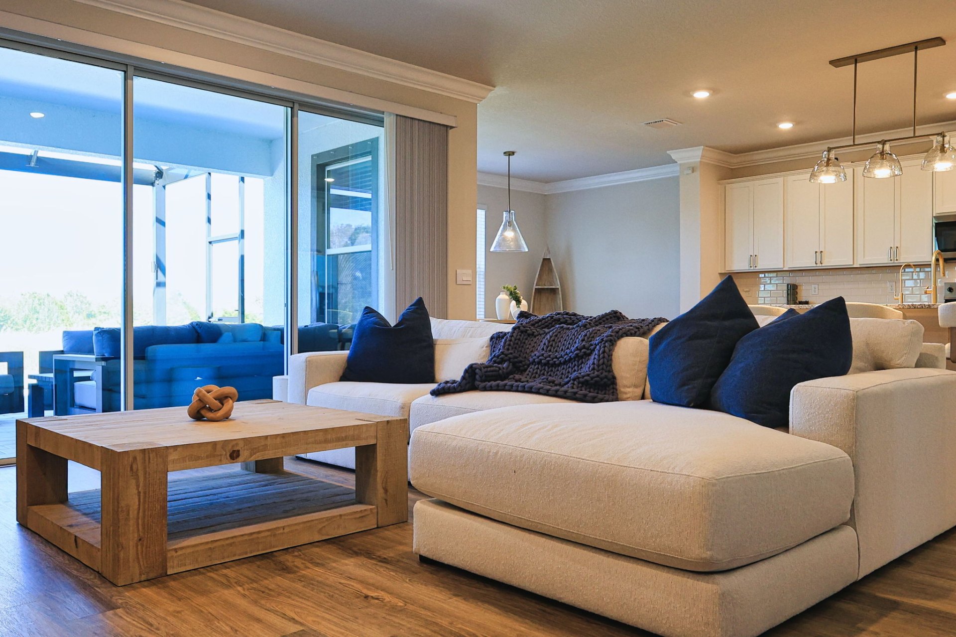 Open-concept living room with cream sectional, navy accent pillows and lanai access