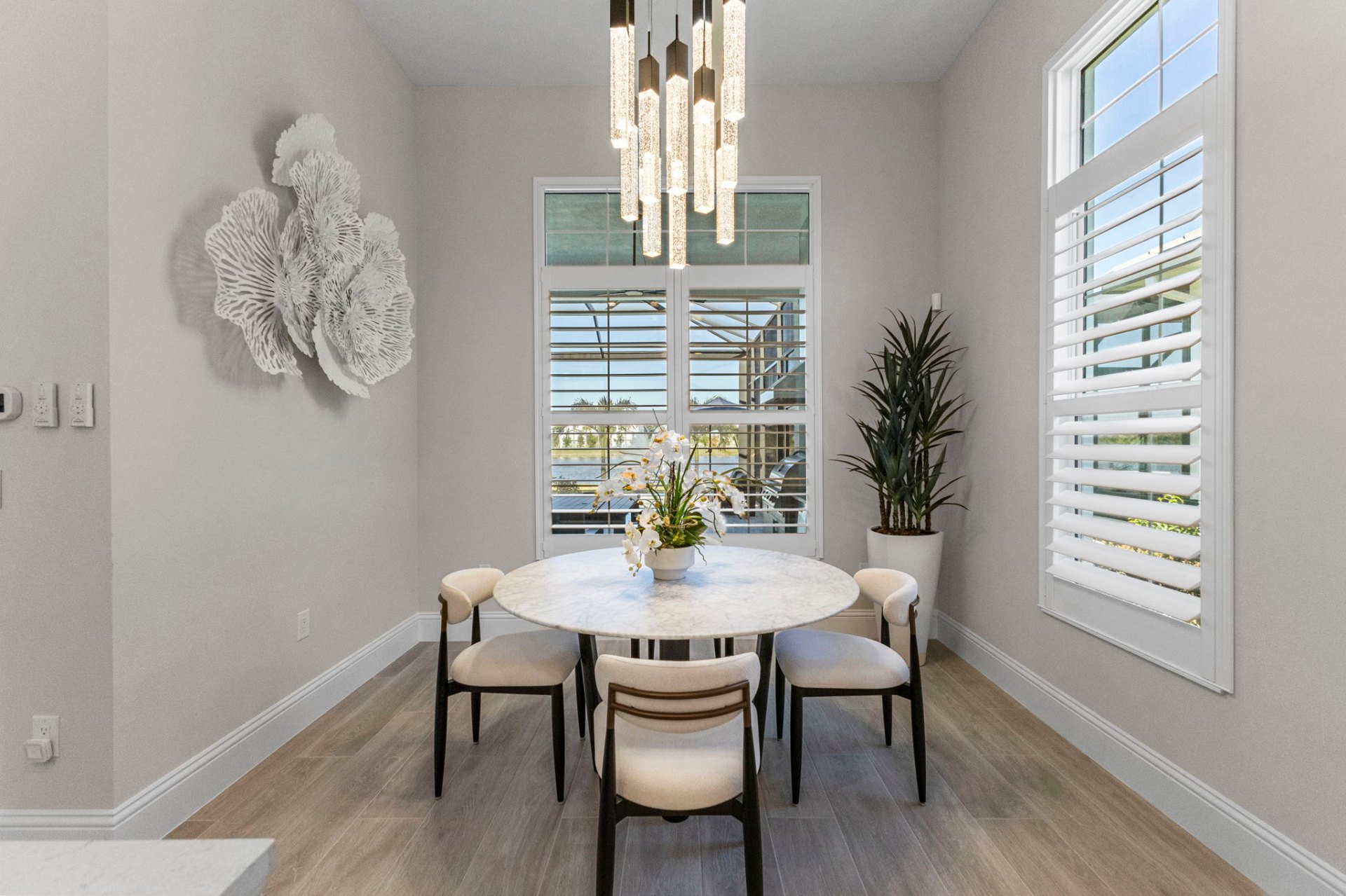 Breakfast nook with round marble table, designer pendants and coral wall art