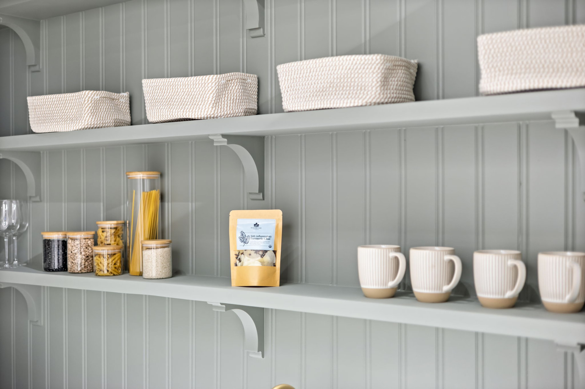 Curated pantry shelves with baskets, canisters and mugs on custom bracketed shelving