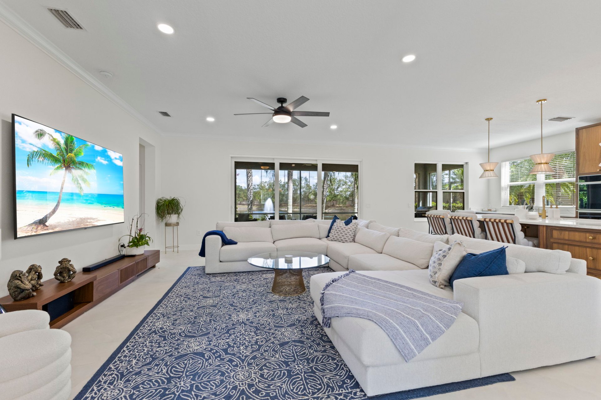 Open-plan family room with oversized sectional opening onto the walnut kitchen and pool views
