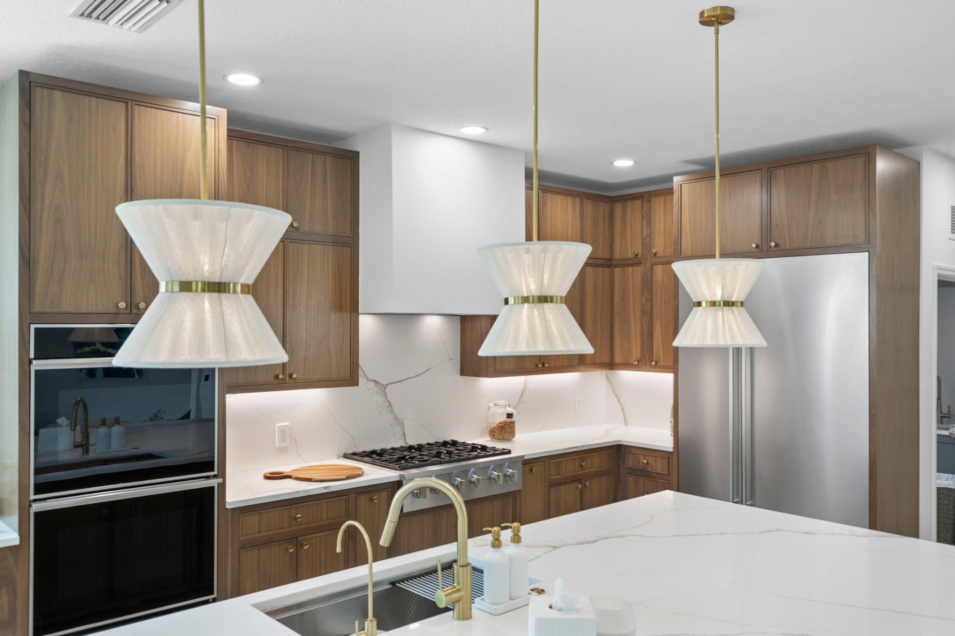 Three sculptural pendants over the island with walnut perimeter cabinetry