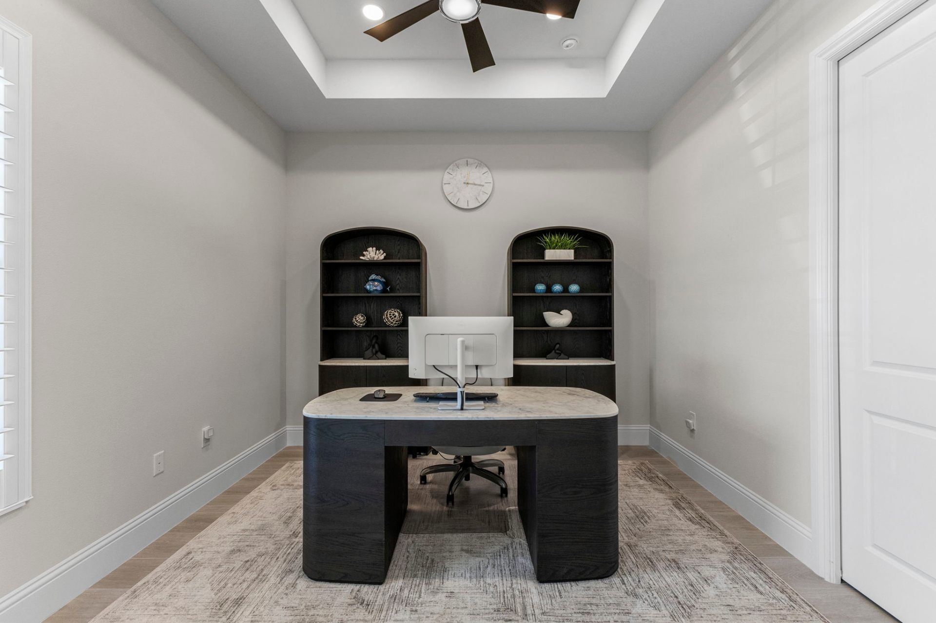 Home office with custom arched built-in bookcases and marble-top desk