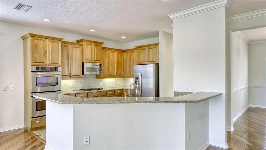Before — original peninsula with granite countertop and maple cabinetry