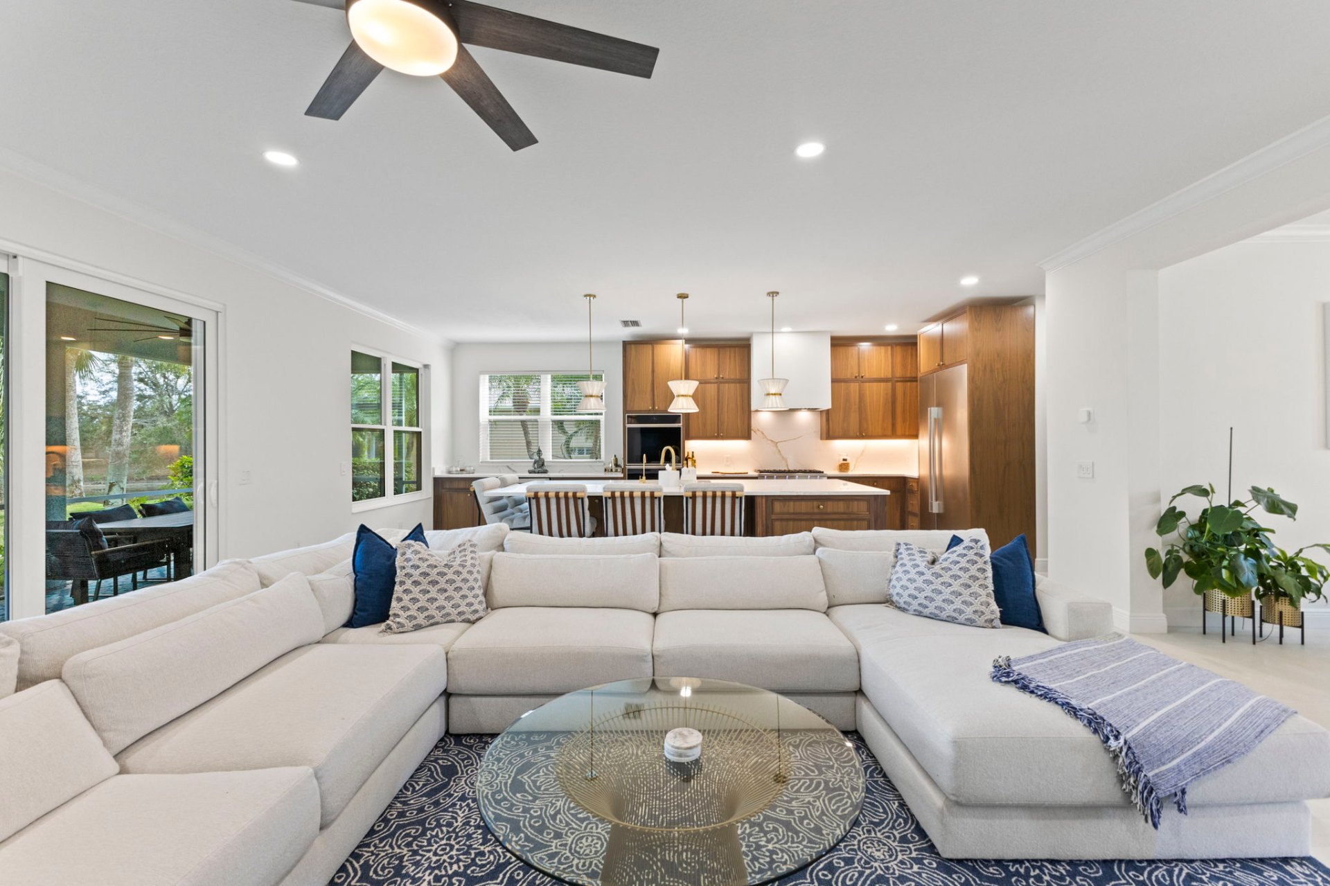Custom-designed living room with sectional sofa, view to lanai and walnut kitchen beyond