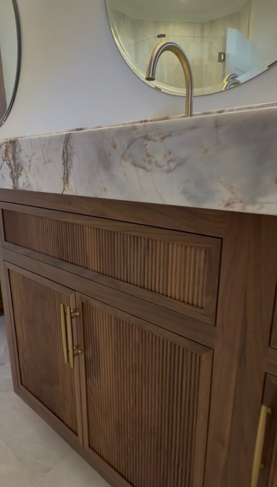 Close detail of fluted walnut door and drawer fronts with brushed brass bar pulls