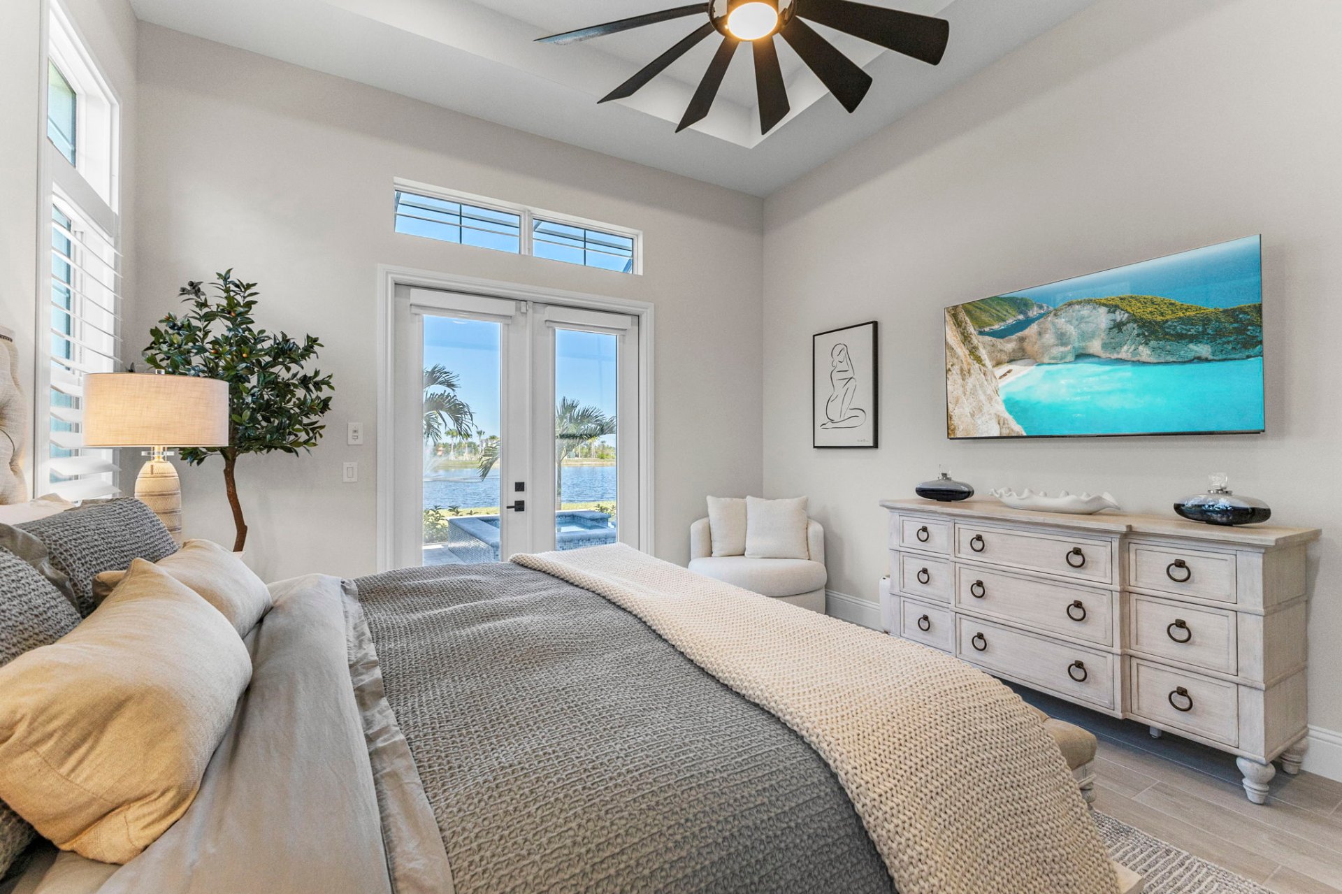 Guest bedroom with lake-view French doors and coastal art