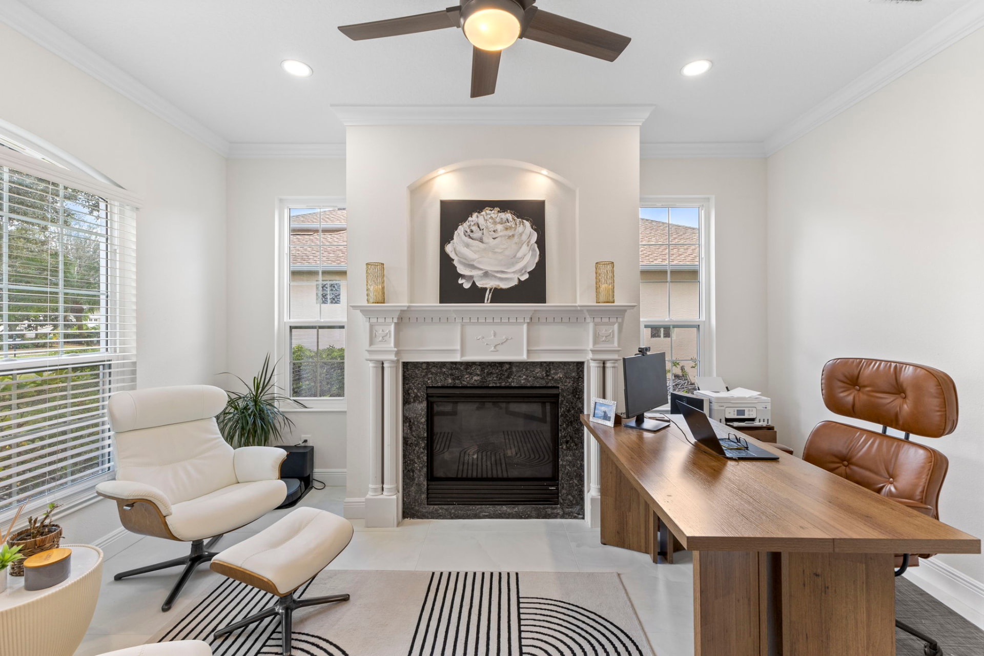 Home office furnished with a walnut desk, tan leather chair and a marble fireplace with floral artwork