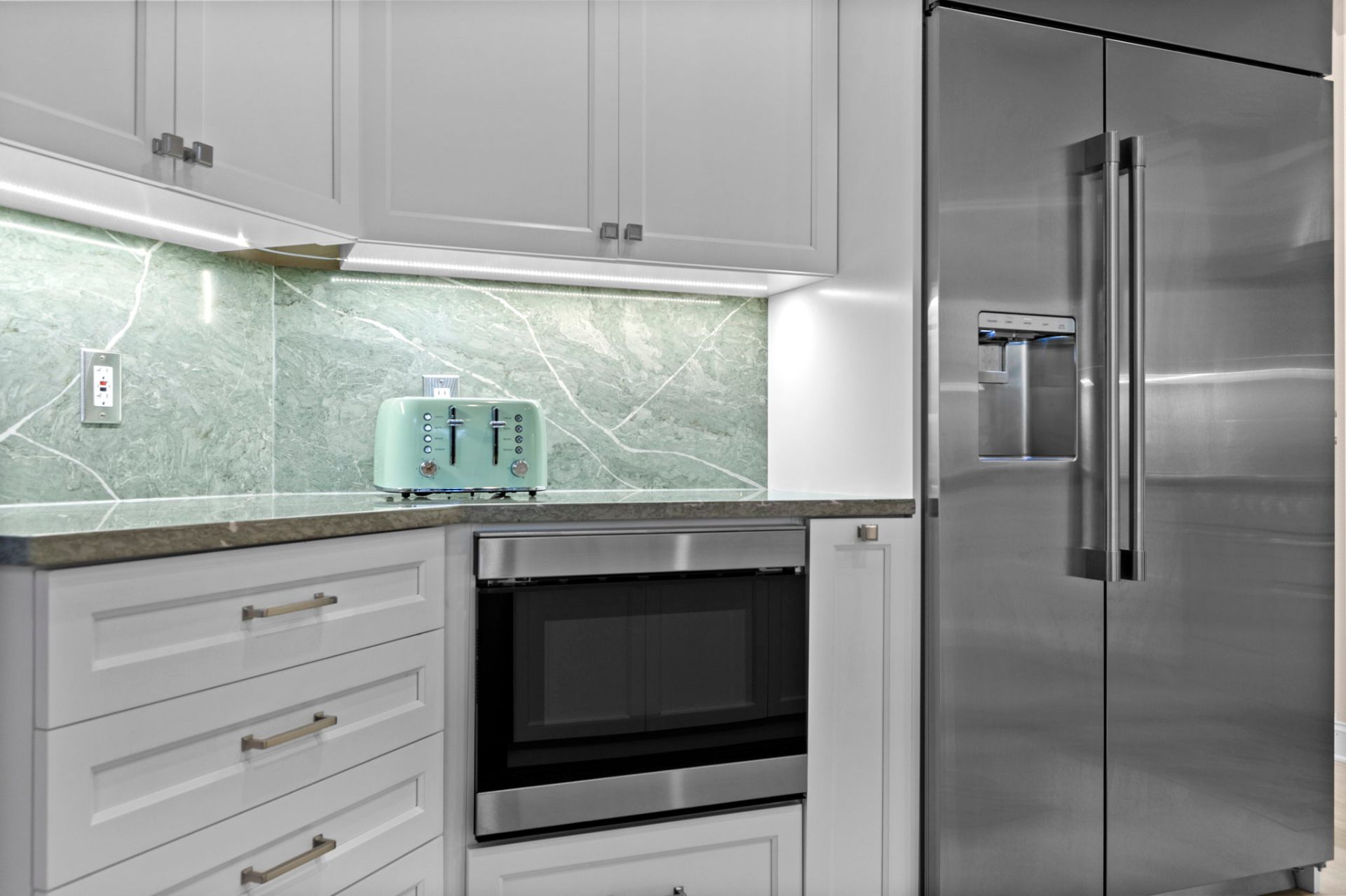 Custom cabinetry with built-in microwave and green stone backsplash