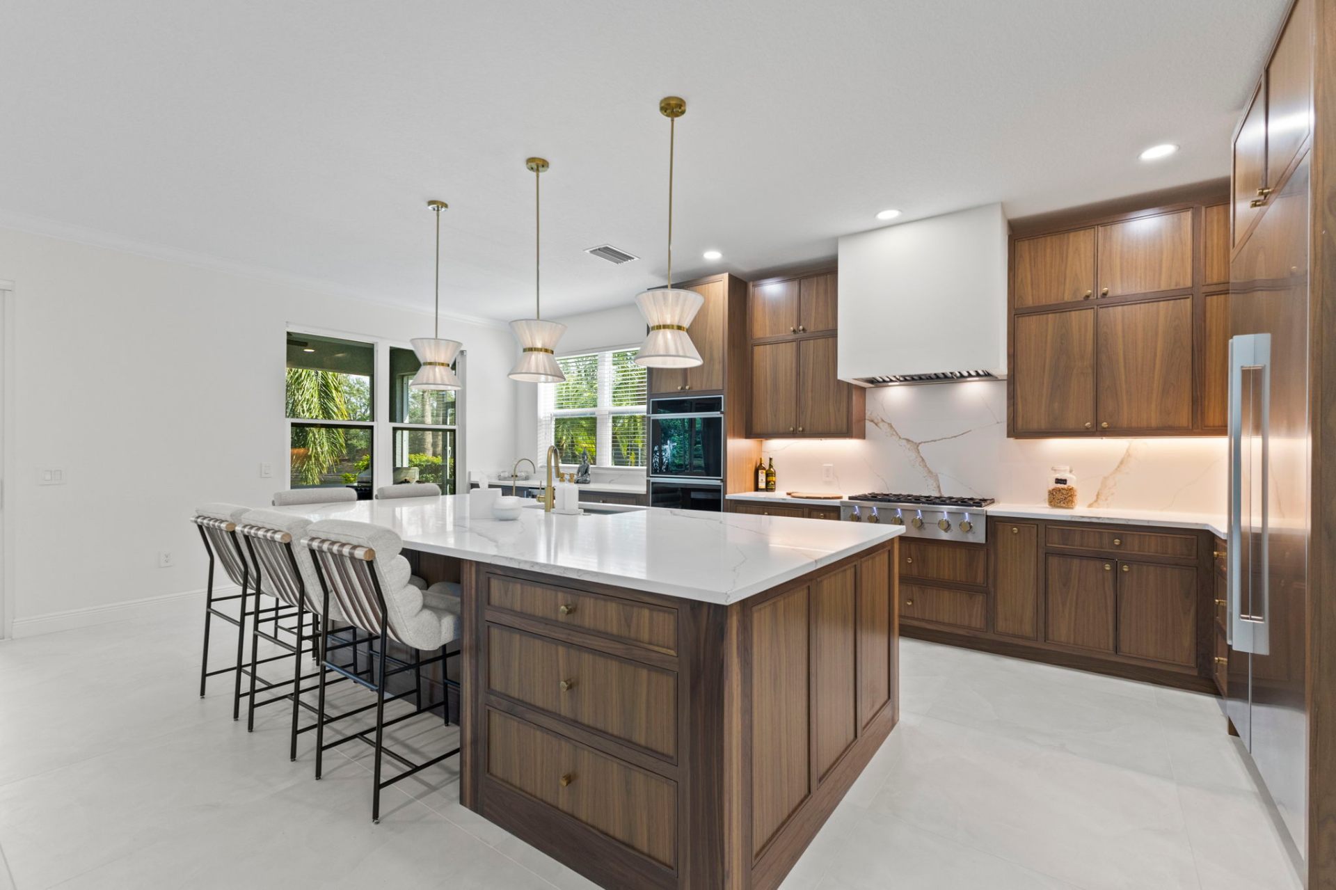 Walnut kitchen with waterfall quartz island and tiered pendant lighting