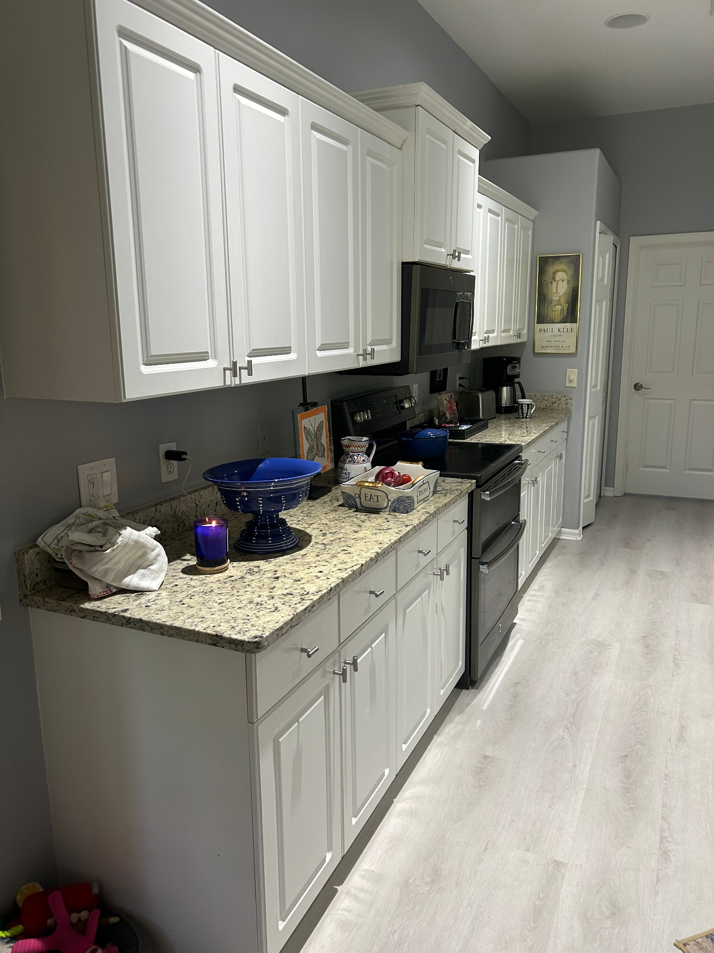 Before — original River Club galley kitchen with white raised-panel cabinetry and granite countertops