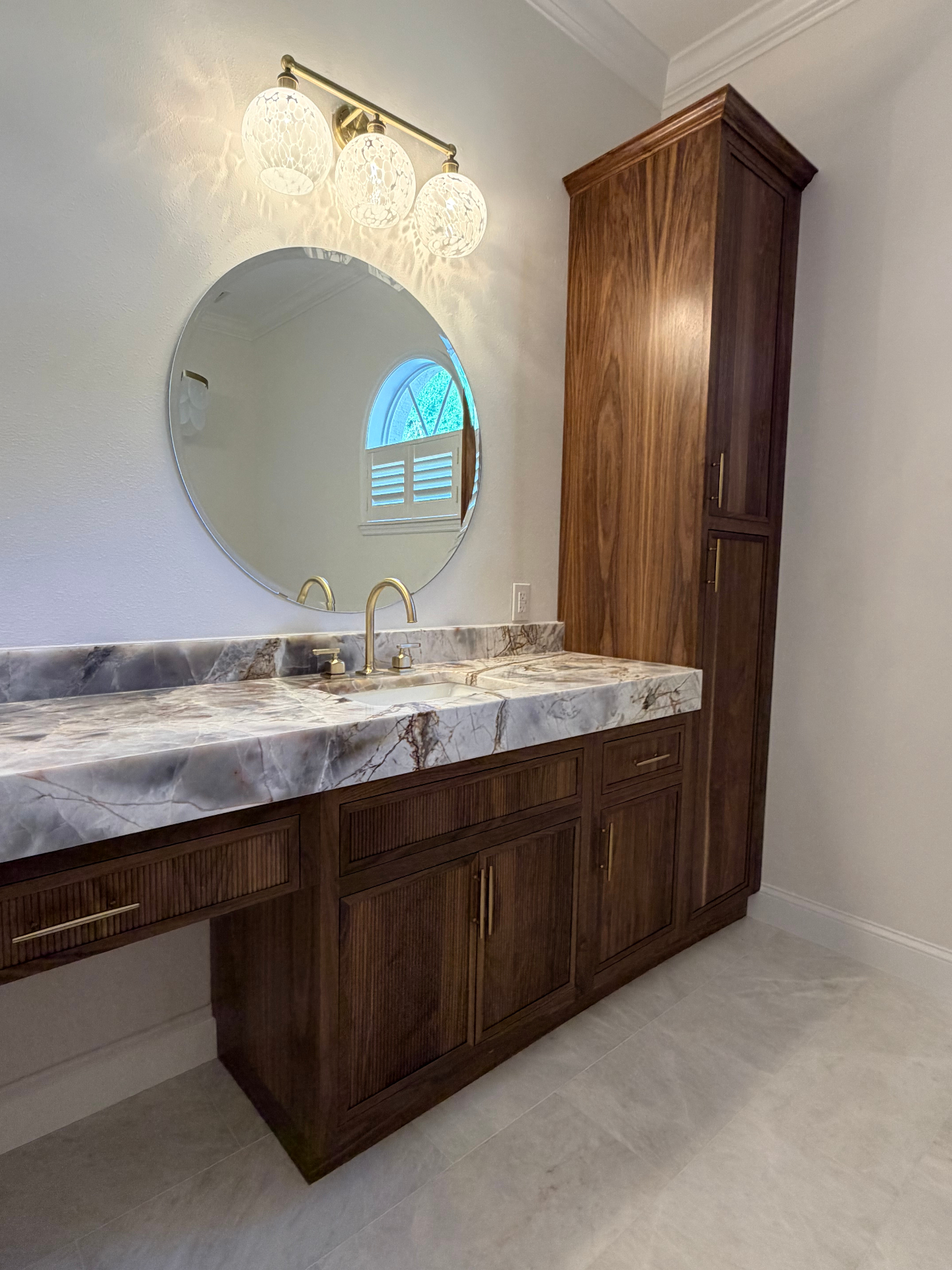 Walnut makeup vanity with fluted drawer fronts, brushed brass hardware and quartzite countertop